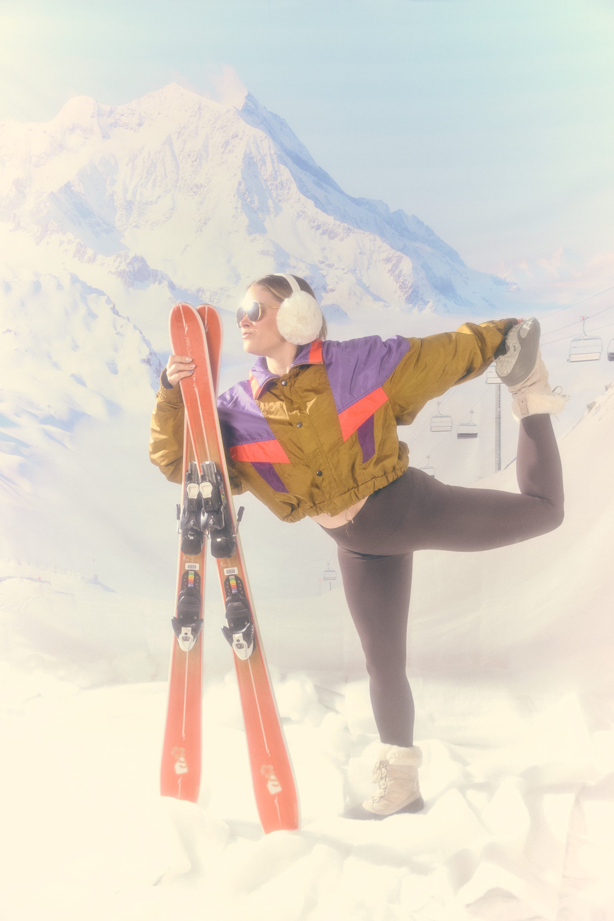 Limber crew member in a retro ski jacket striking a yoga pose on the slopes